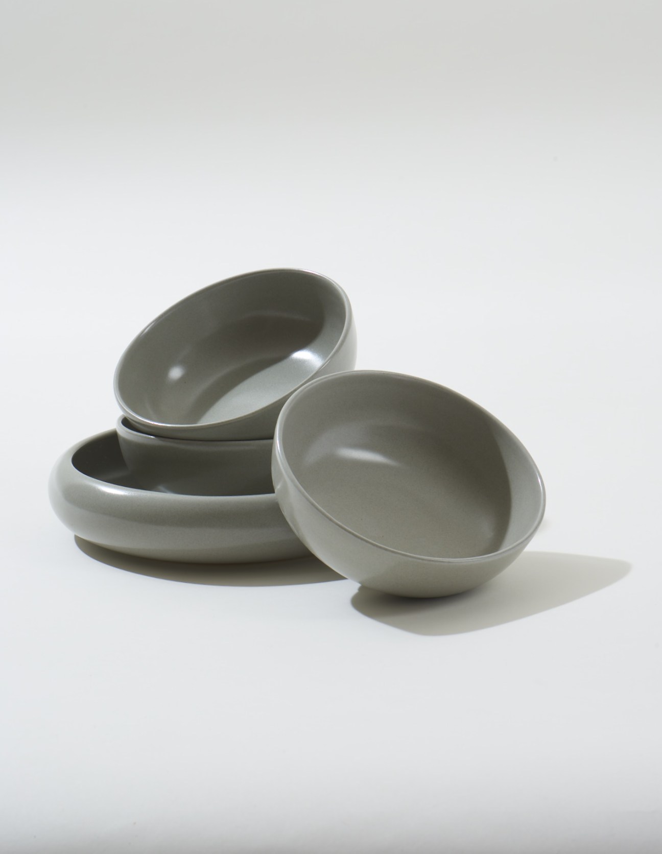 Four ceramic bowls by Gidon Bing in neutral tones stacked and arranged on a white surface.