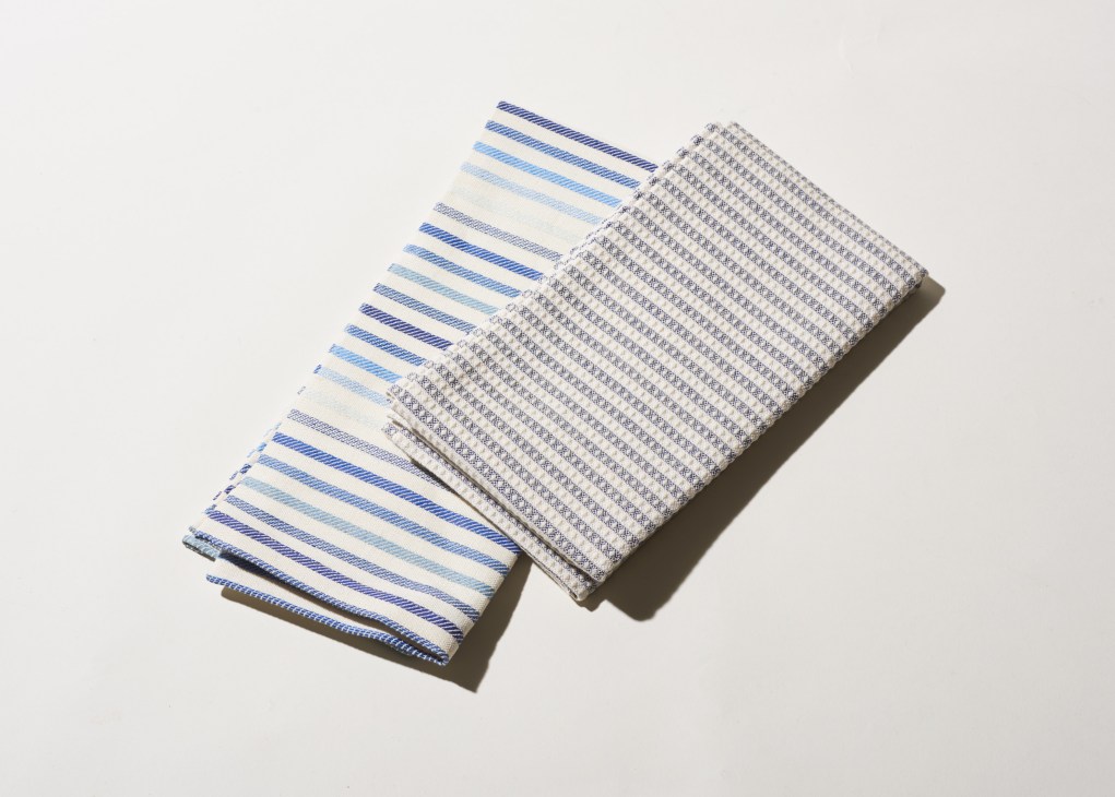 Two folded textiles with blue striped and geometric patterned designs by Chiarastella Cattana.