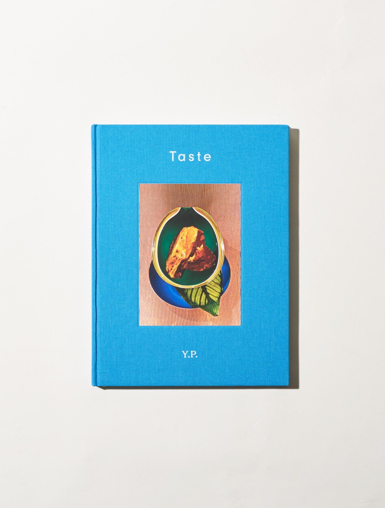 Blue hardcover book titled 'Taste' by Yabu Pushelberg with illustrated fish design on cover.