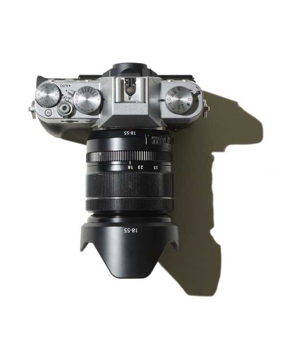 Overhead view of a Fujifilm X-T20 mirrorless camera with silver top plate and black lens against white background.