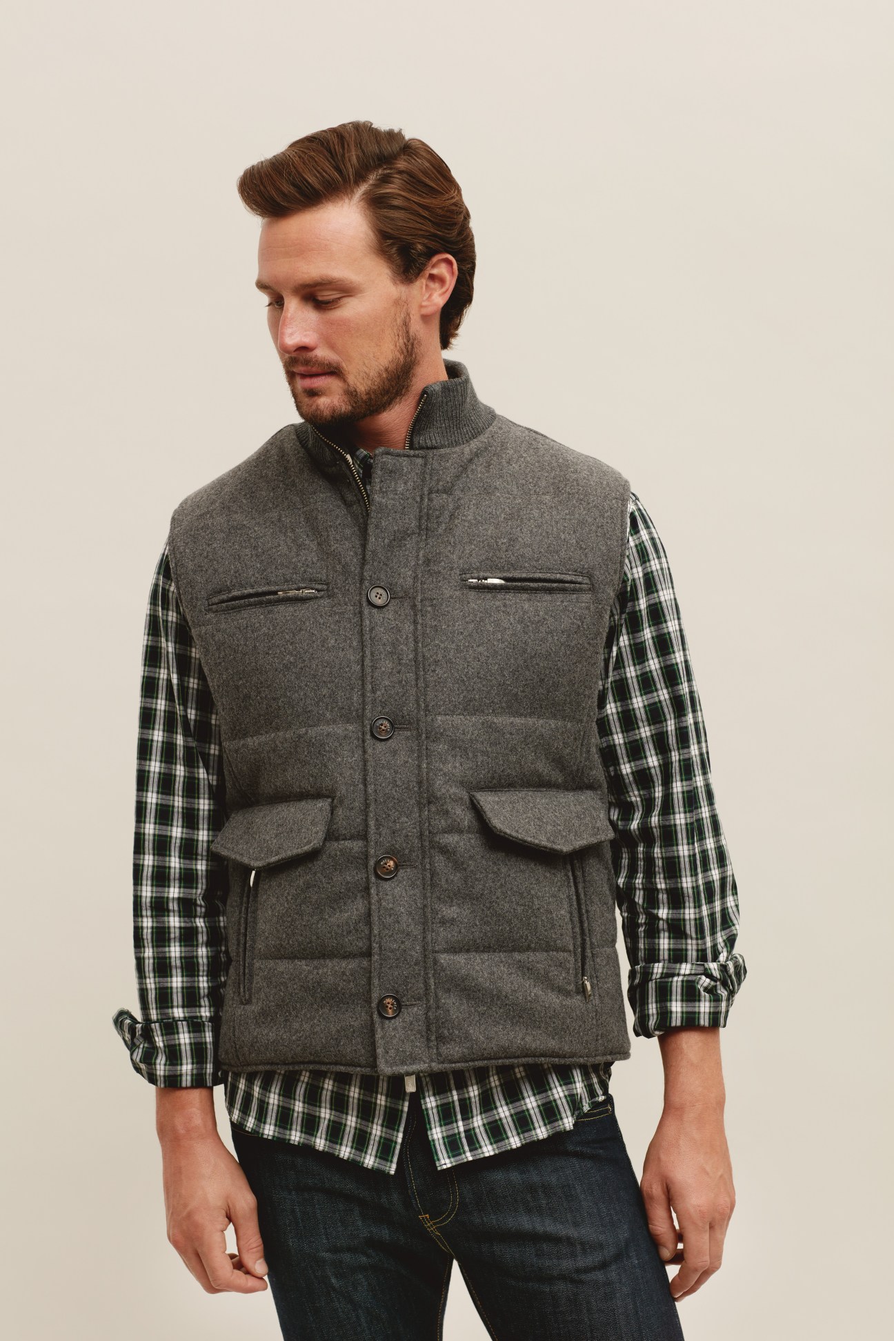 Man wearing grey wool vest over plaid shirt and dark trousers