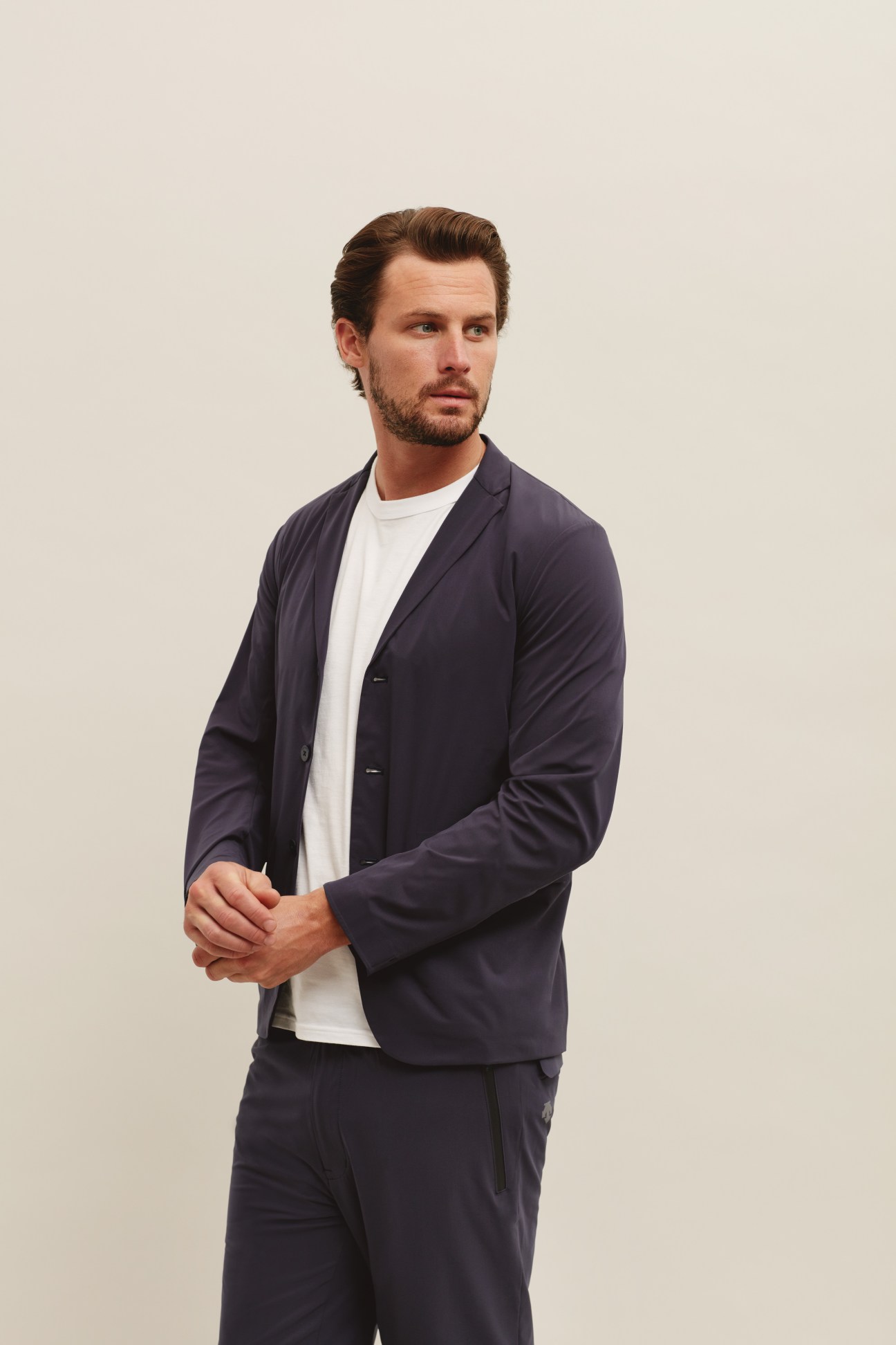 Man wearing a light-colored Descente Blanc Pause travel jacket over a white t-shirt