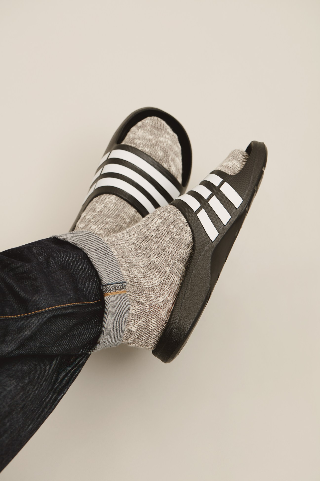 Person wearing grey wool socks with black and white striped sneakers and dark jeans.