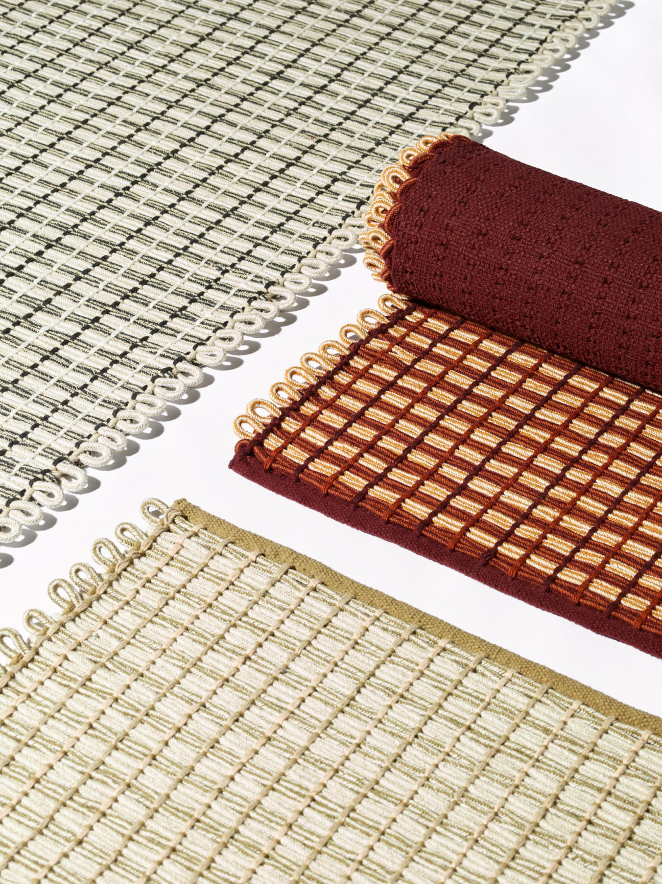 Rolled rope rugs in neutral cream and burgundy with decorative edging displayed against white background.
