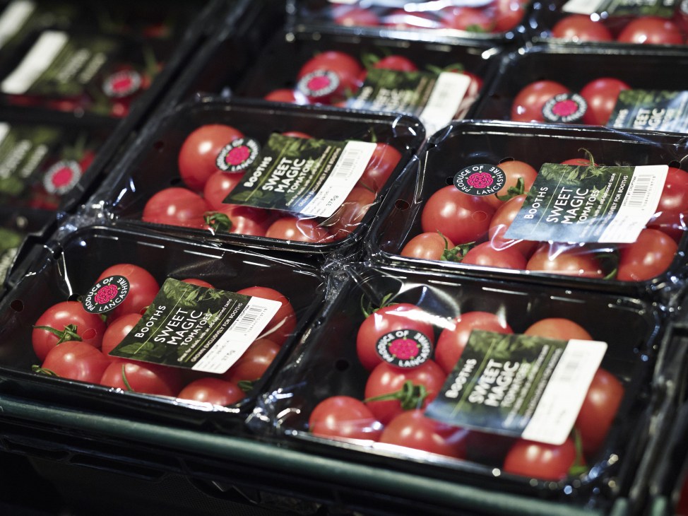 Packaged tomatoes with Booths branding displayed on black trays in a store shelf.
