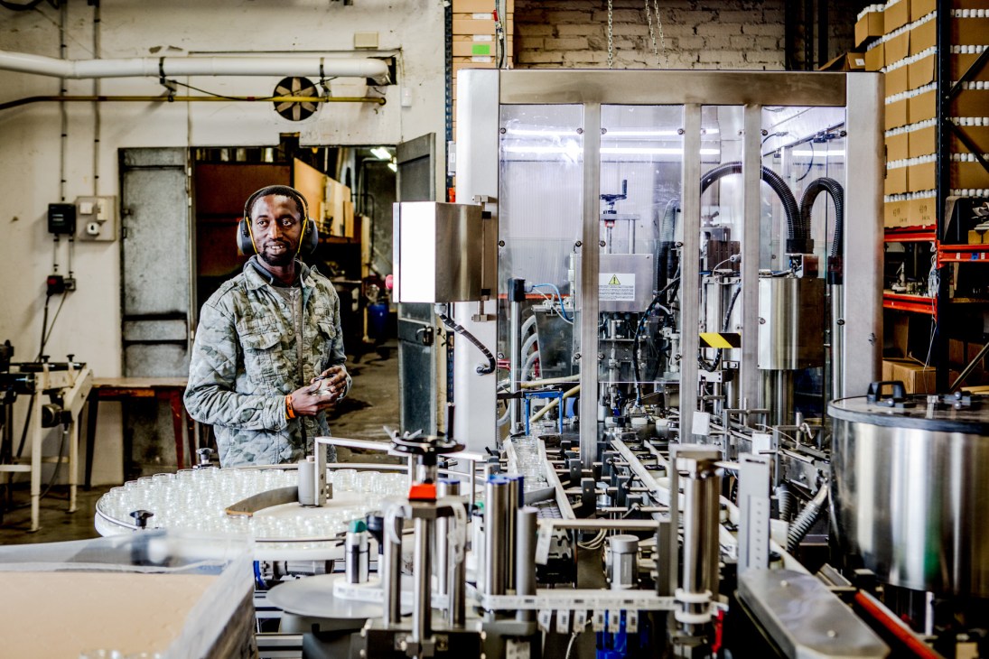 Famaco factory worker standing next to sticker assembly line machinery.