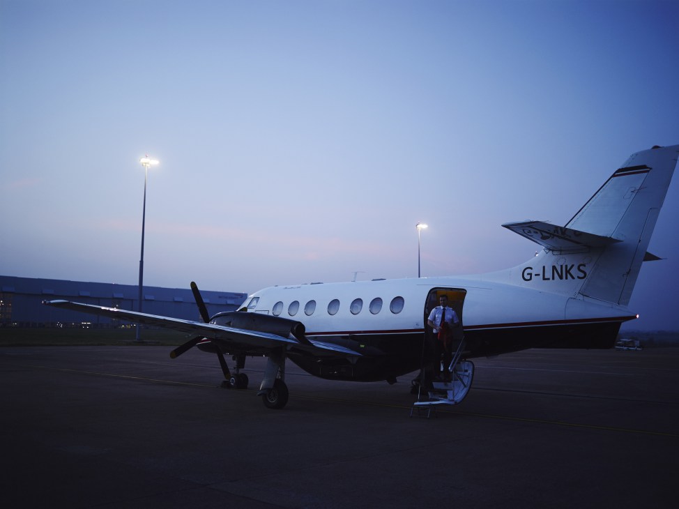Links Air twin-prop aircraft G-LNKS parked at Anglesey airport at dusk with ground lighting.