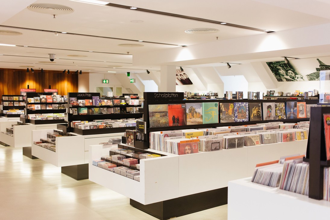Interior of Ludwig Beck department store in Munich showing white and black retail display units with vinyl records and music merchandise.