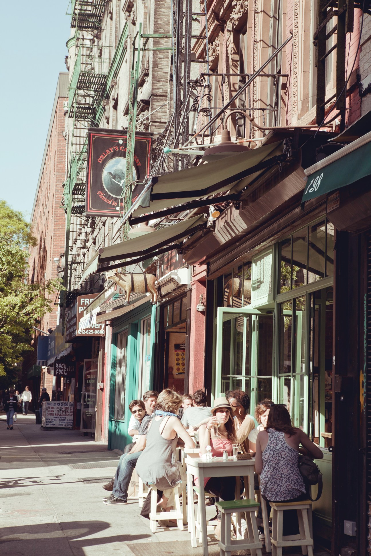Customers seated at outdoor tables on a Chinatown street with historic buildings and storefronts in the background.