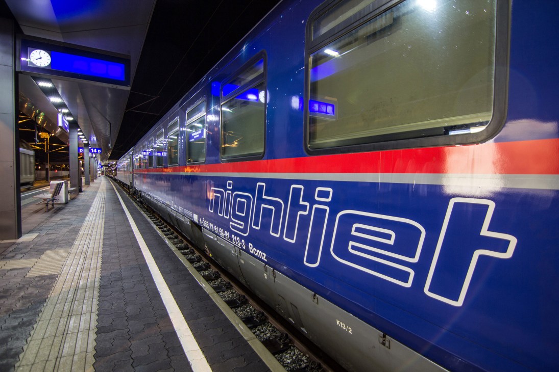 ÖBB Nightjet train at platform with blue and red livery at night