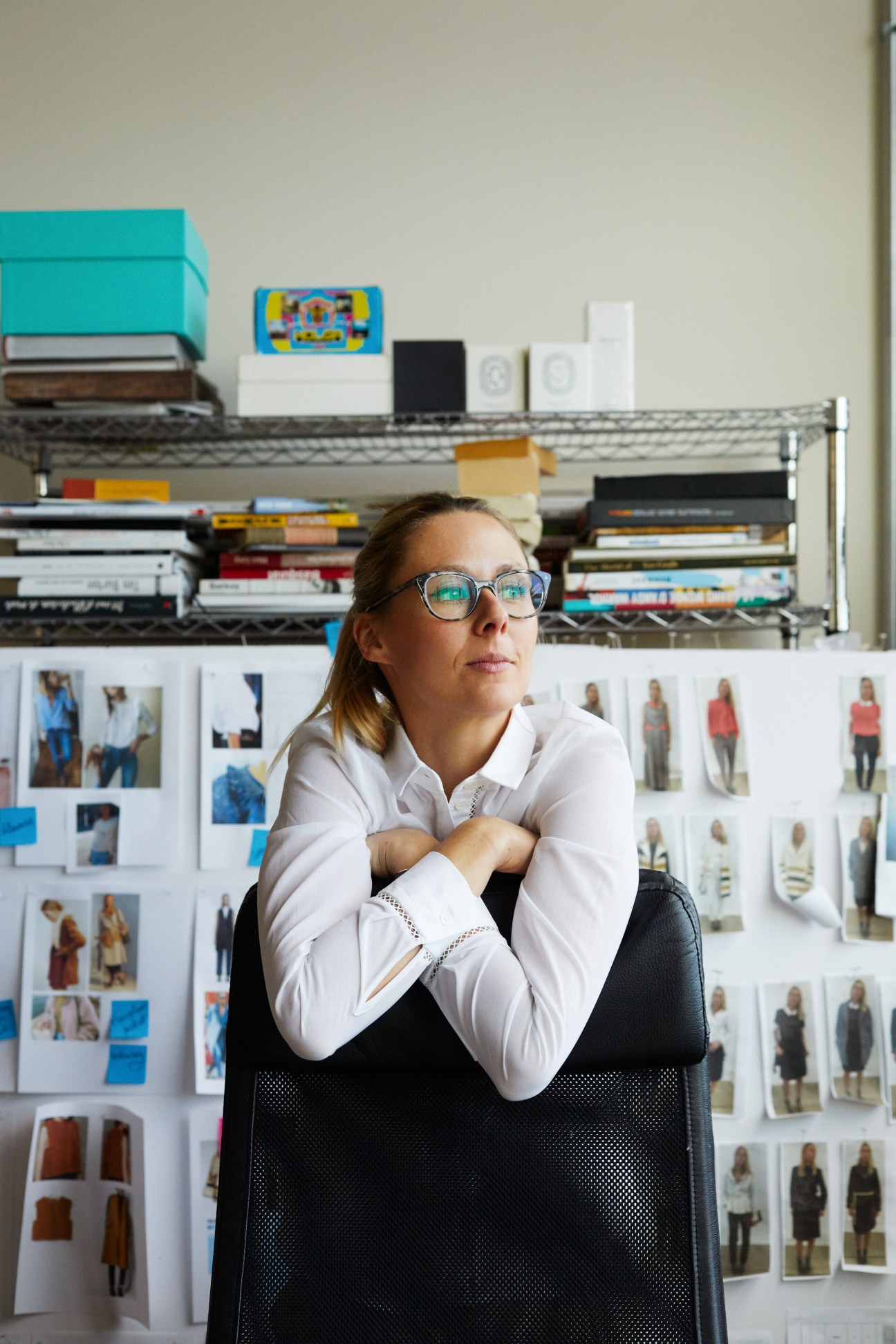 Woman designer in studio with mood boards and design references behind her.