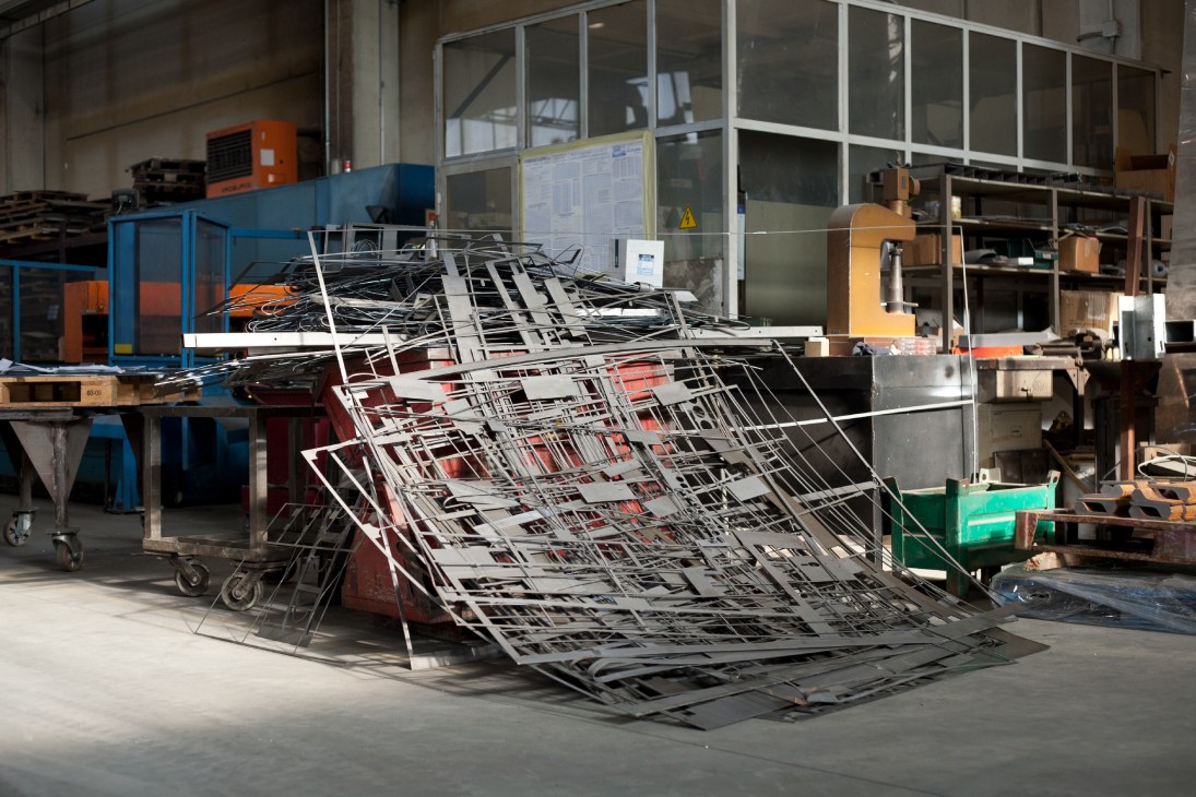 Laser-cut steel panels and components stacked in an industrial workshop at Parma Antonio & Figli.