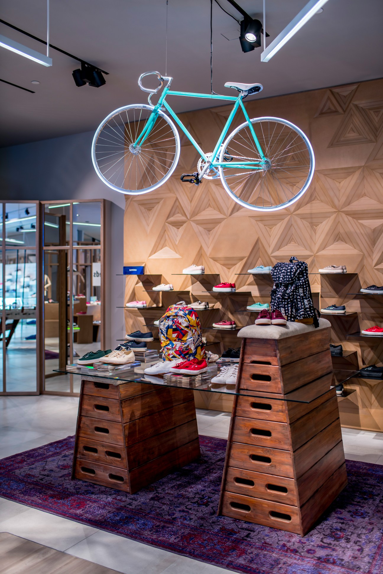 Interior of Pedder on Scotts Singapore shoe retailer with neon-lit turquoise bicycle and wooden display fixtures.