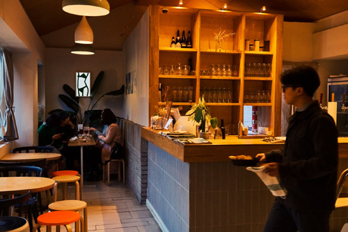 Interior of Strukt café with shelves of books, warm lighting, and customers seated at tables.