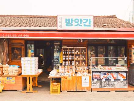 Exterior of 1913 Songjeong Station Market with traditional storefront displaying soju bottles and dried goods.