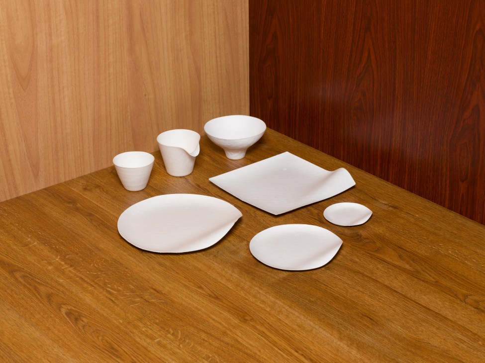 Wasara's white paper plates, bowls and cups arranged on a wooden table.