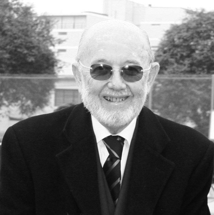 Portrait of Frederick Cooper, an older man with white hair and beard wearing sunglasses, dark suit and striped tie.