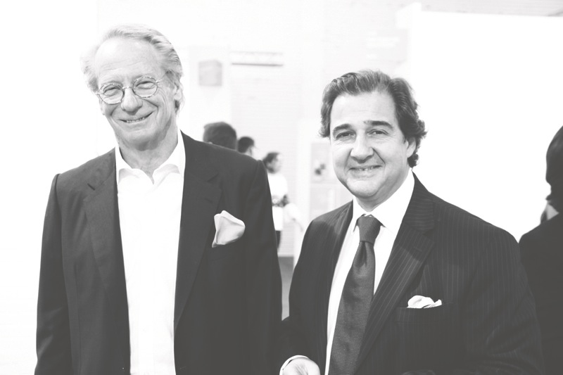 Two men in formal business attire at what appears to be an art event or gallery opening.