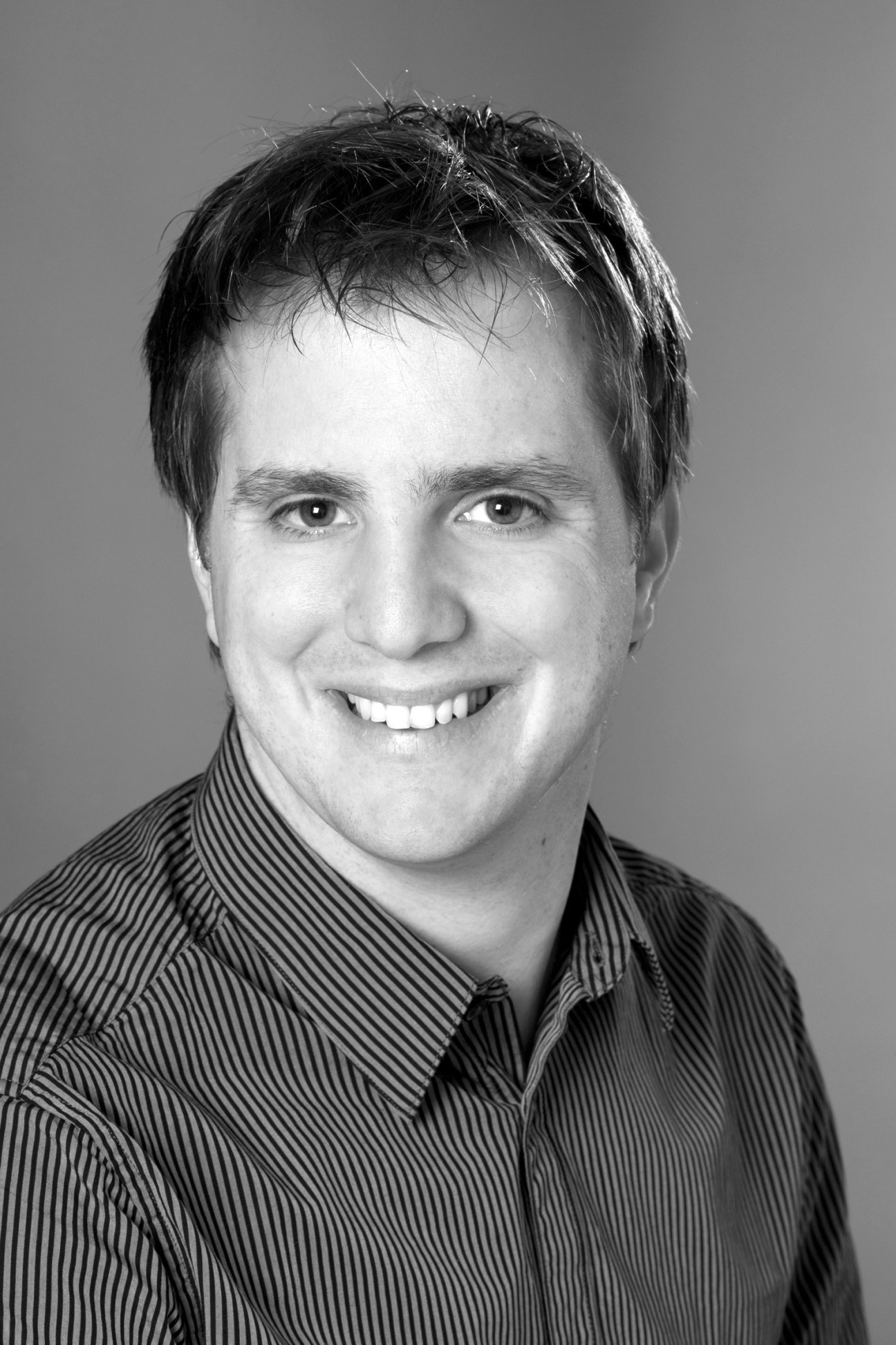 Black and white portrait photograph of Christian Vögeli, CEO of Dybuster, wearing a striped shirt.