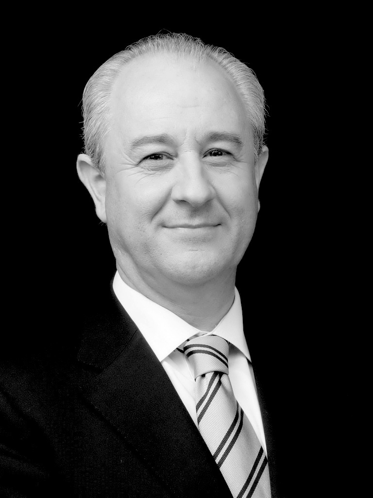 Black and white portrait of Rui Rio, Mayor of Porto, wearing a dark suit and striped tie.