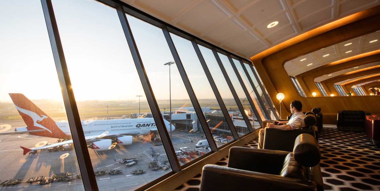 Qantas First Class lounge at Sydney Airport with floor-to-ceiling windows overlooking tarmac and aircraft.