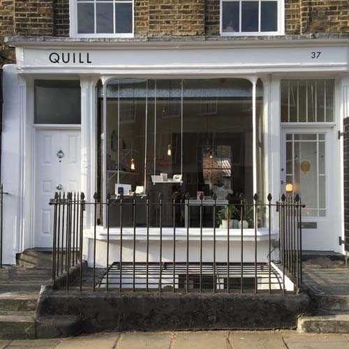 Quill stationery shop storefront in London with white frame and black railings.