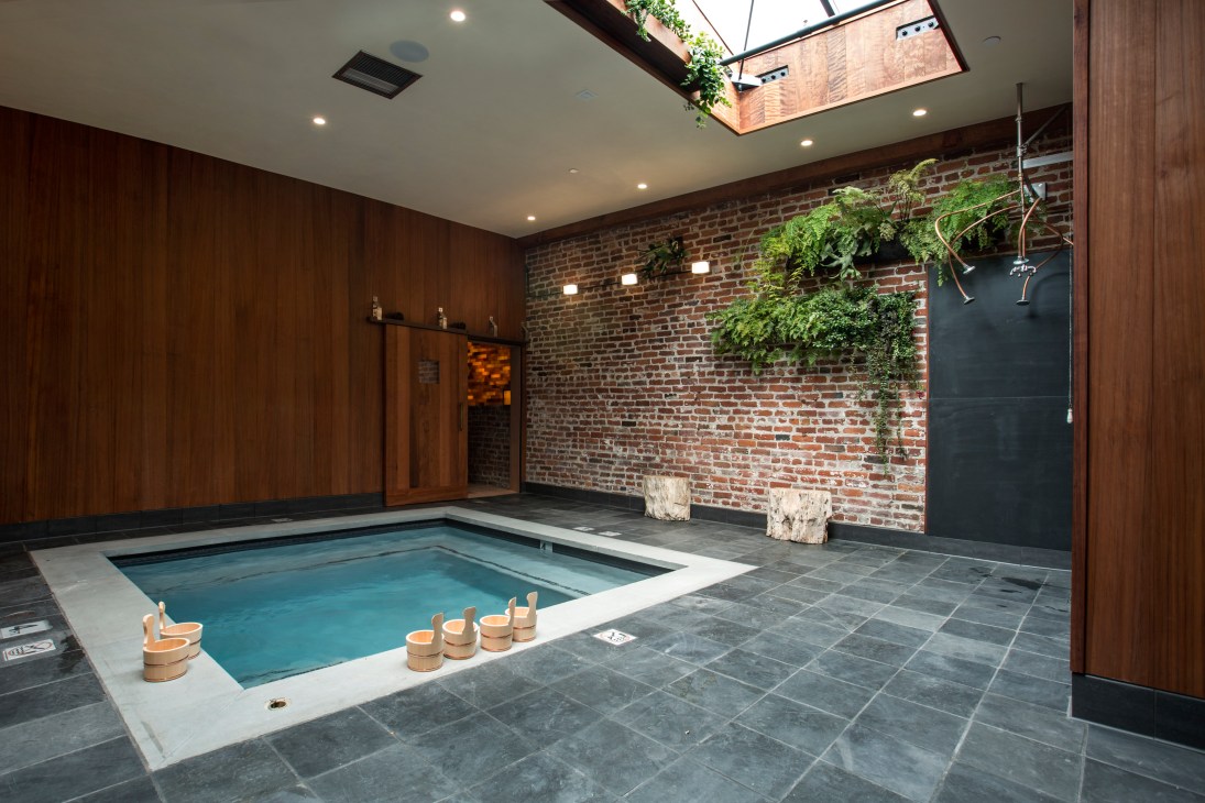 Interior of Onsen spa in San Francisco showing a hot spring pool with wooden buckets and skylight.