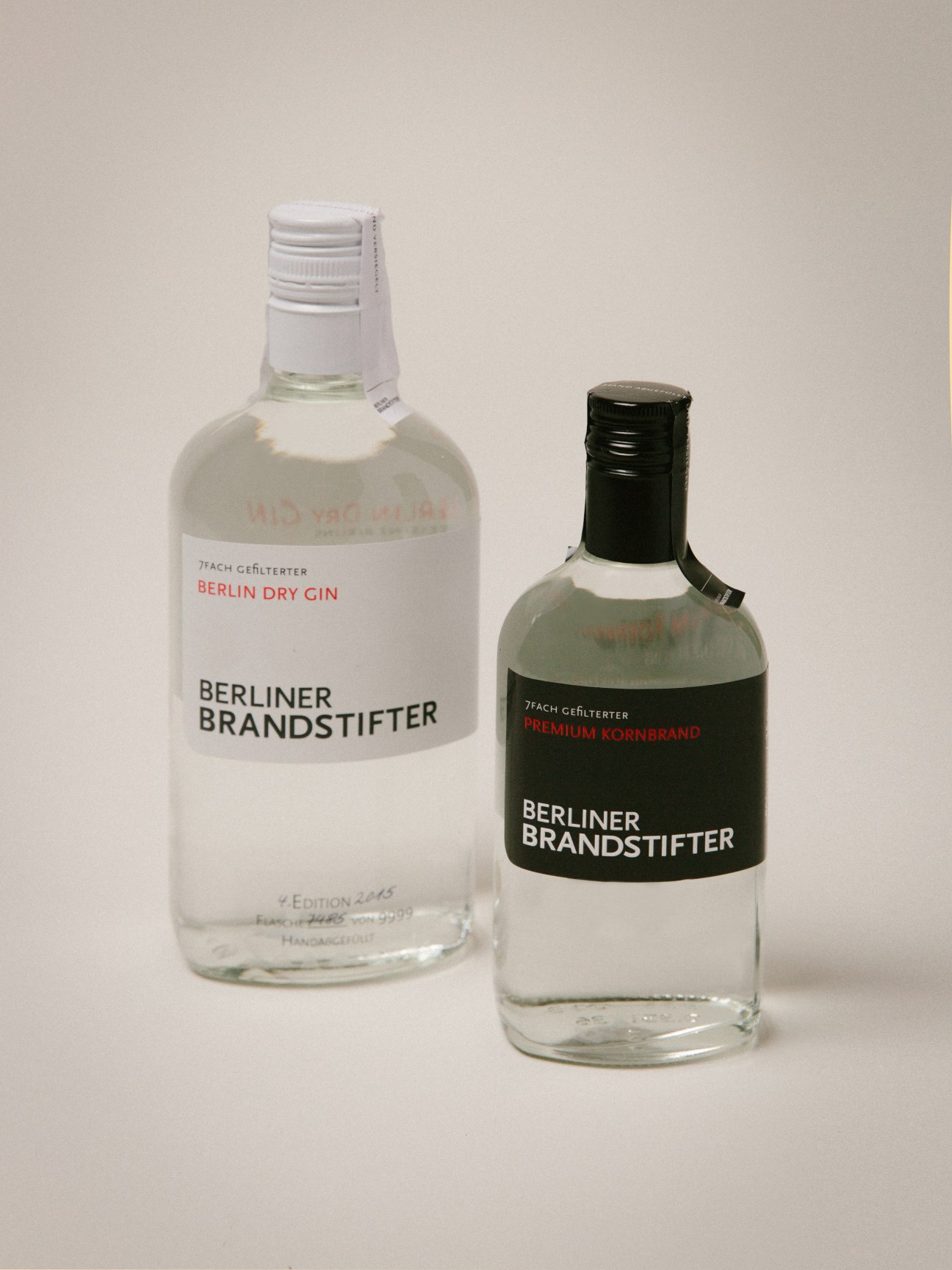 Two bottles of Berliner Brandstifter gin and kornbrand with white and black labels.