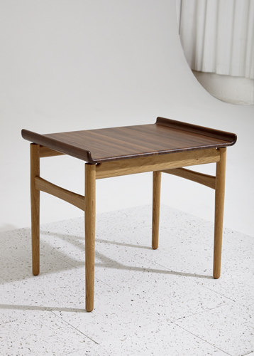 Hans J Wegner coffee table in dark walnut with curved lines and tapered wooden legs.