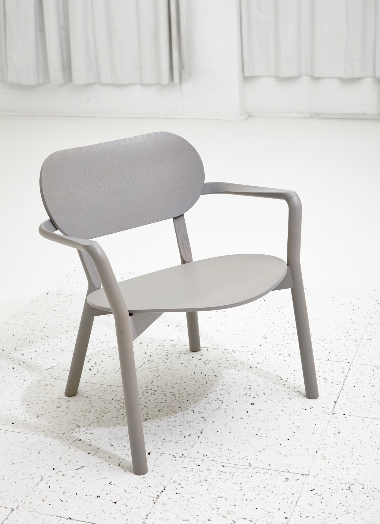 Castor low chair in light oak with rounded backrest and armrests by Big Game for Karimoku New Standard.