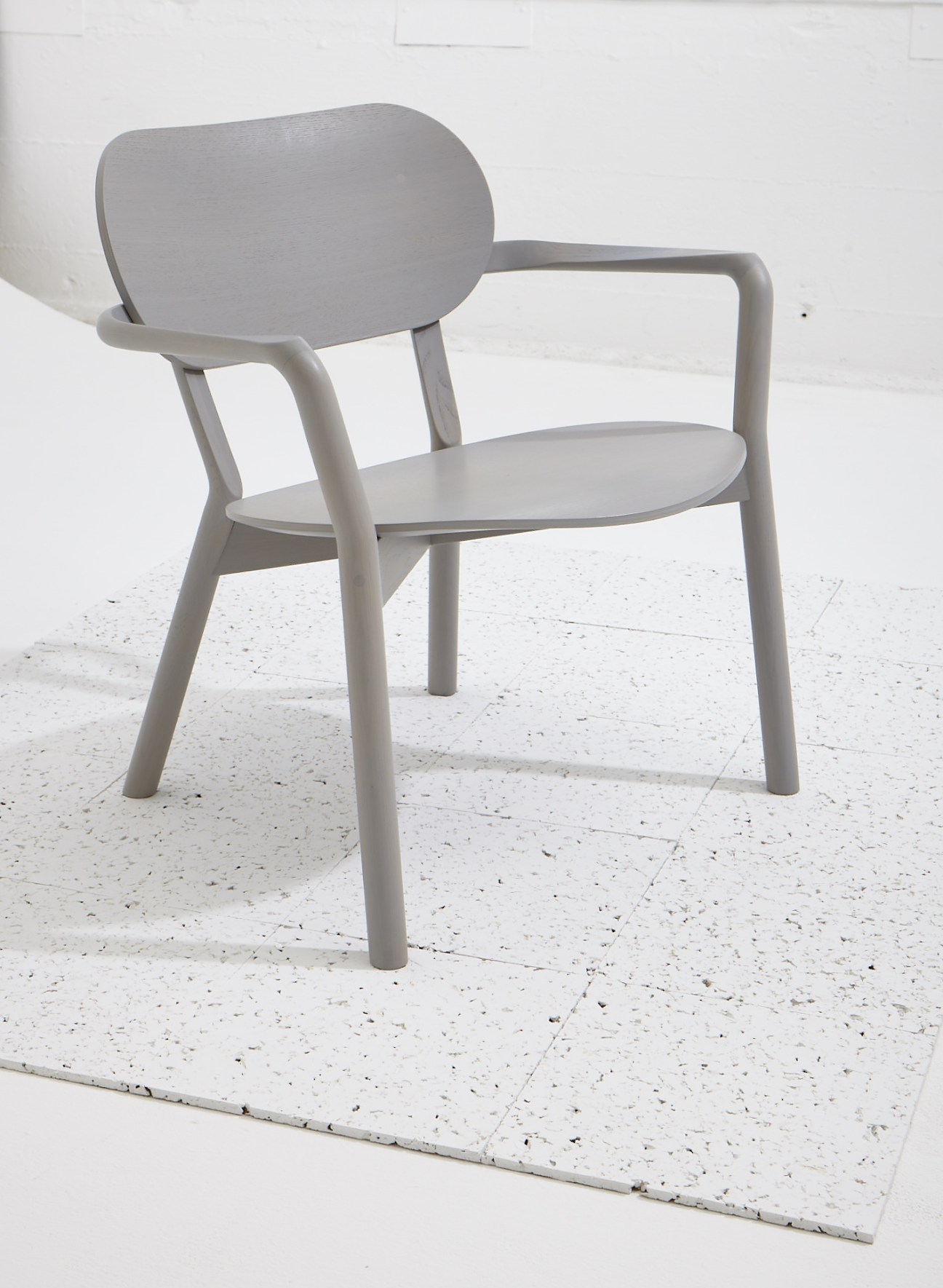Coupé chair by Poiat for Woud in light gray wood with curved backrest and armrests.