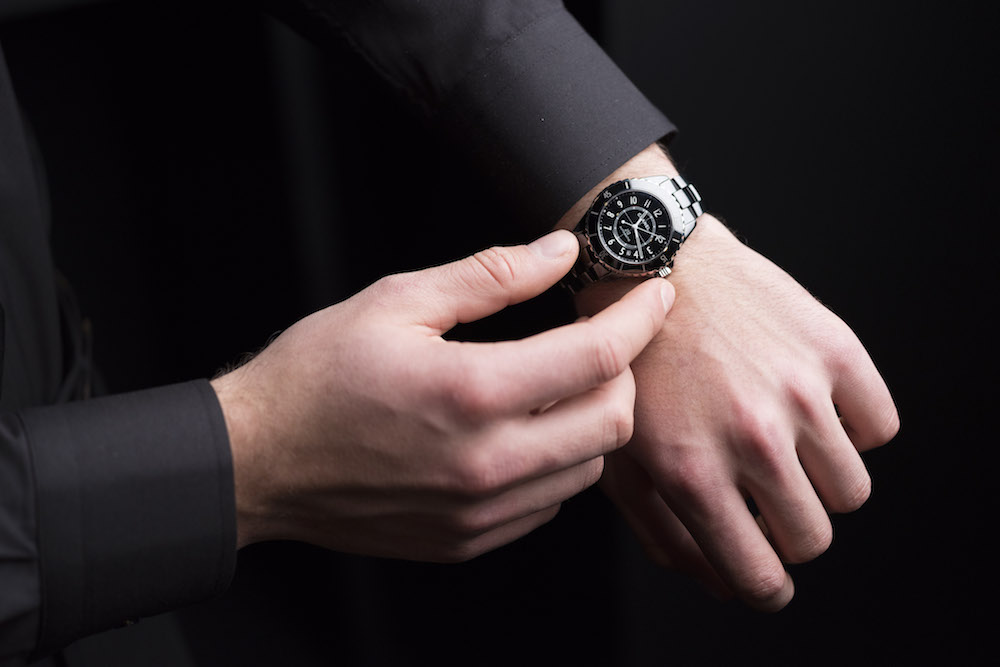 Man in black suit displaying a Chanel J12 watch with refined bezel on his wrist
