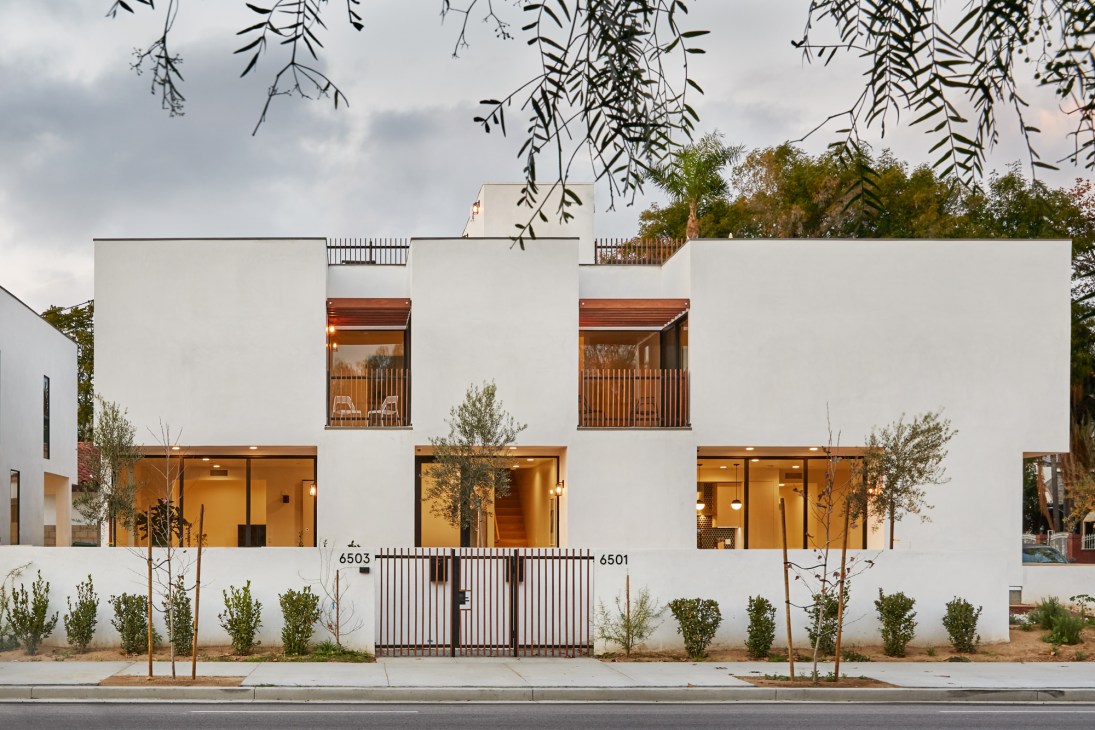 Modern white residential building with wood-framed windows and ground-floor commercial space in Los Angeles.