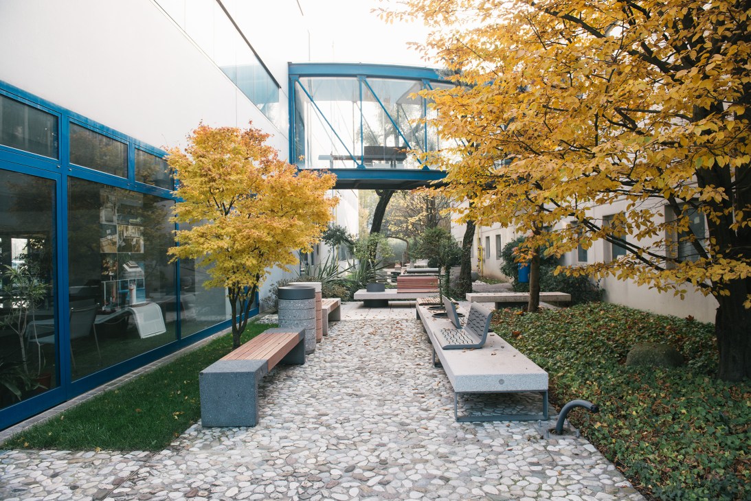 Metalco's outdoor showroom with benches, planters and trees in autumn setting.
