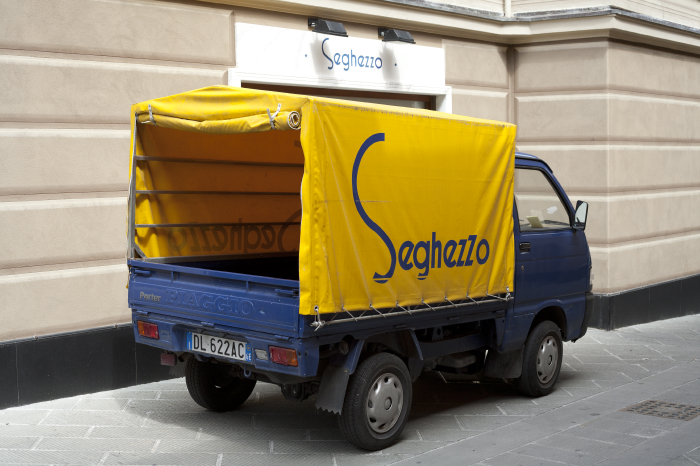 Seghezzo delivery scooter with yellow branded canopy parked outside the shop in Santa Margherita Ligure.