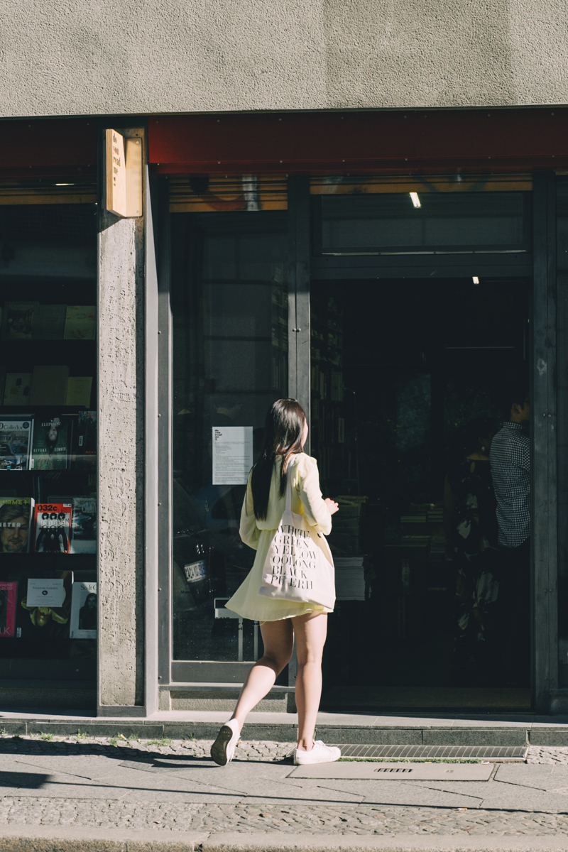 Woman entering Do You Read Me?! magazine shop in Berlin carrying a white shopping bag.