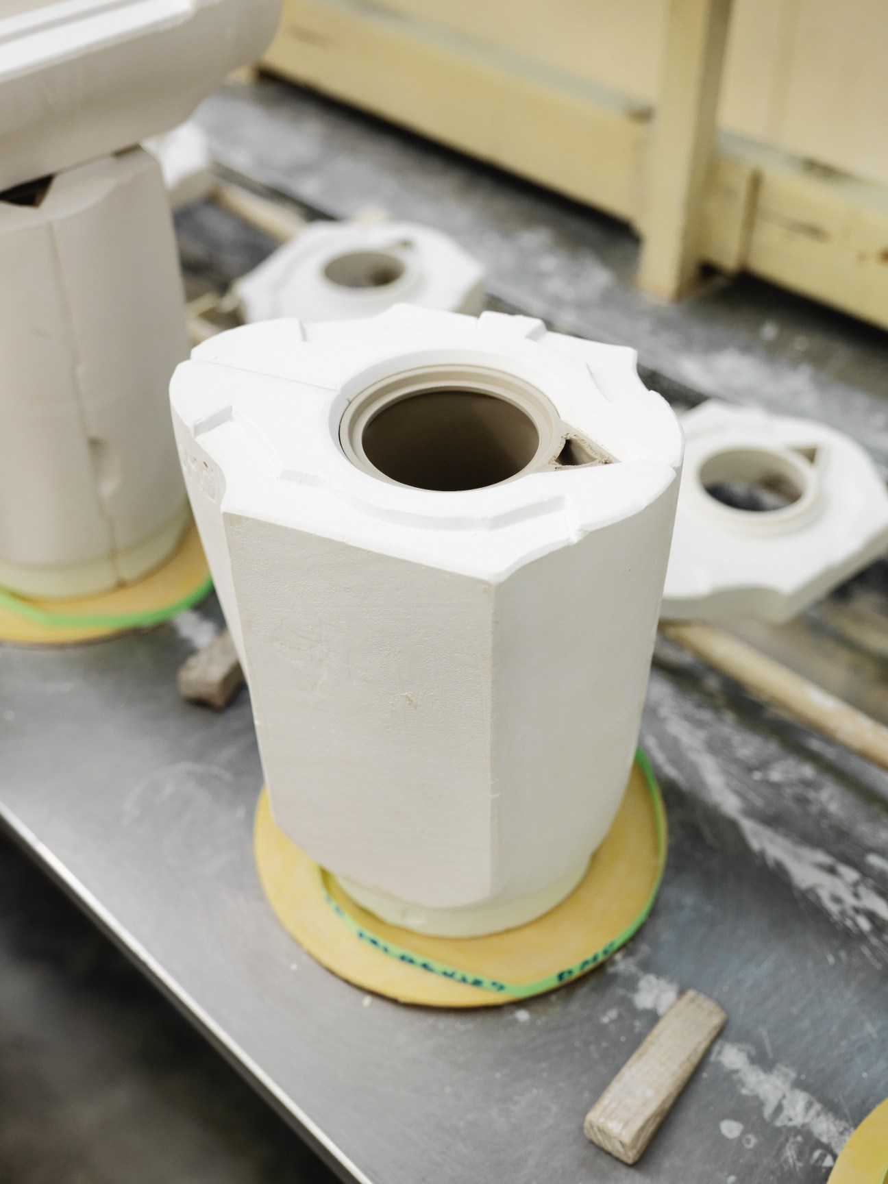 White porcelain slip-cast vessel on a yellow base during the manufacturing process at Vista Alegre factory.