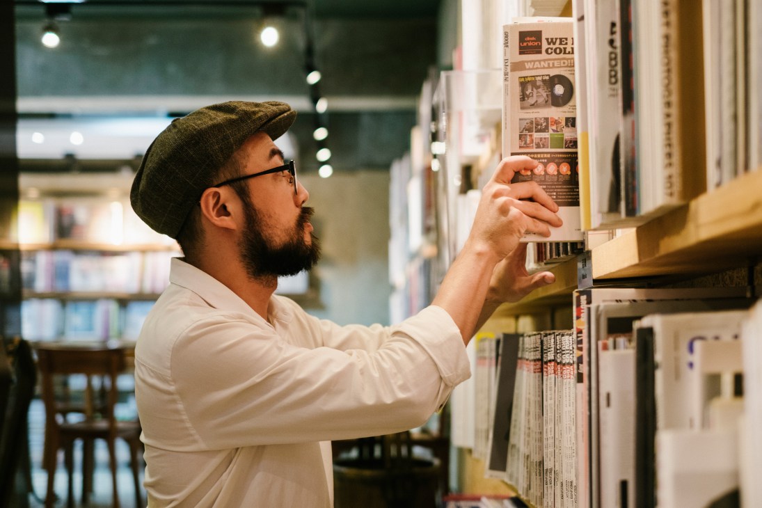 Man browsing magazines on shelves at Boven, a membership library in Taipei.