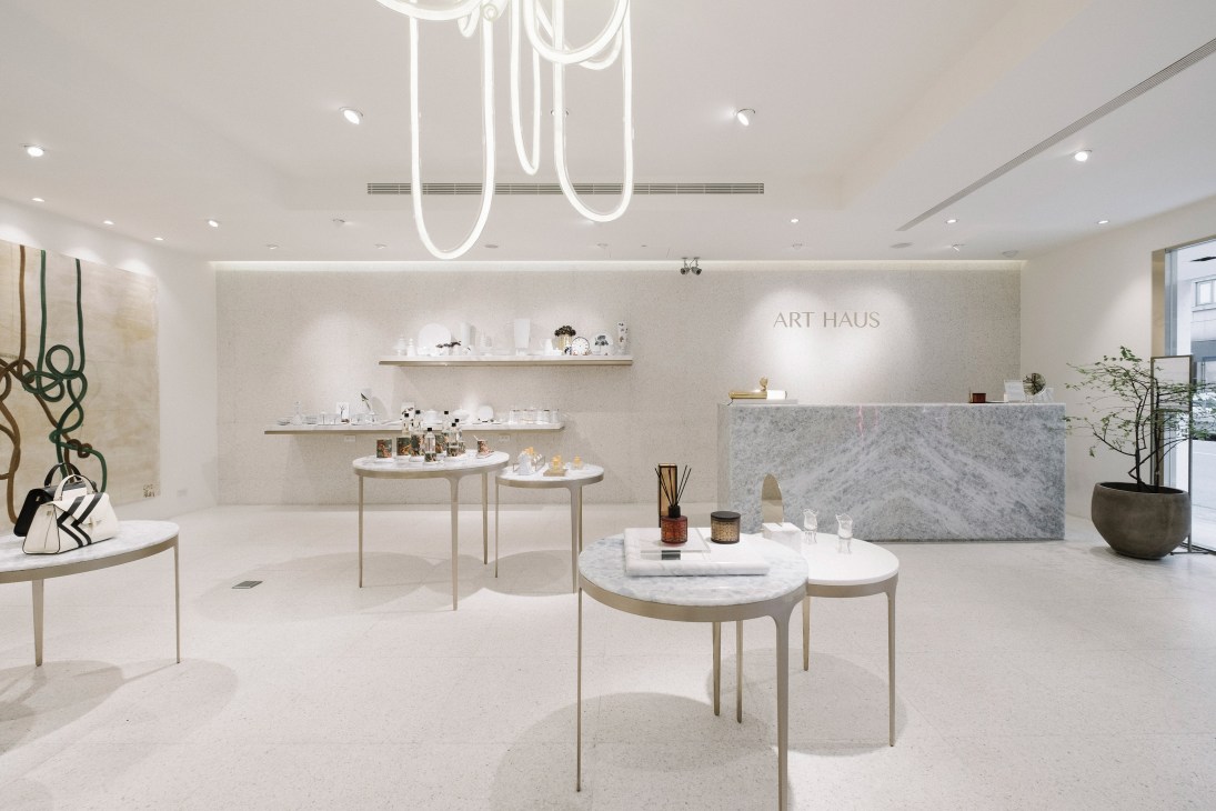 Art Haus showroom interior with neon signage, marble counter, and curated design products displayed on minimalist tables.