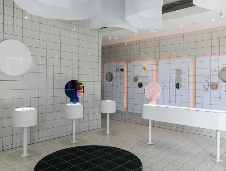 Kirsten Goss jewelry store interior with white tiled walls, display pedestals, and illuminated jewelry pieces.
