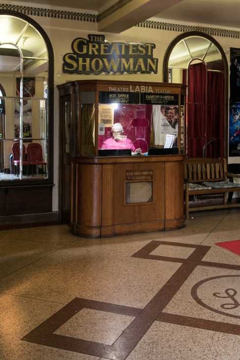 The Labia theatre box office with vintage wooden counter and signage displaying "The Greatest Showman" movie poster.