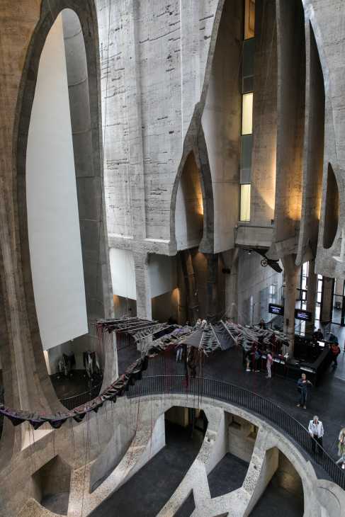 Interior of Zeitz Mocaa gallery showing concrete curved architectural elements and an art installation with fabric draped across the atrium space.