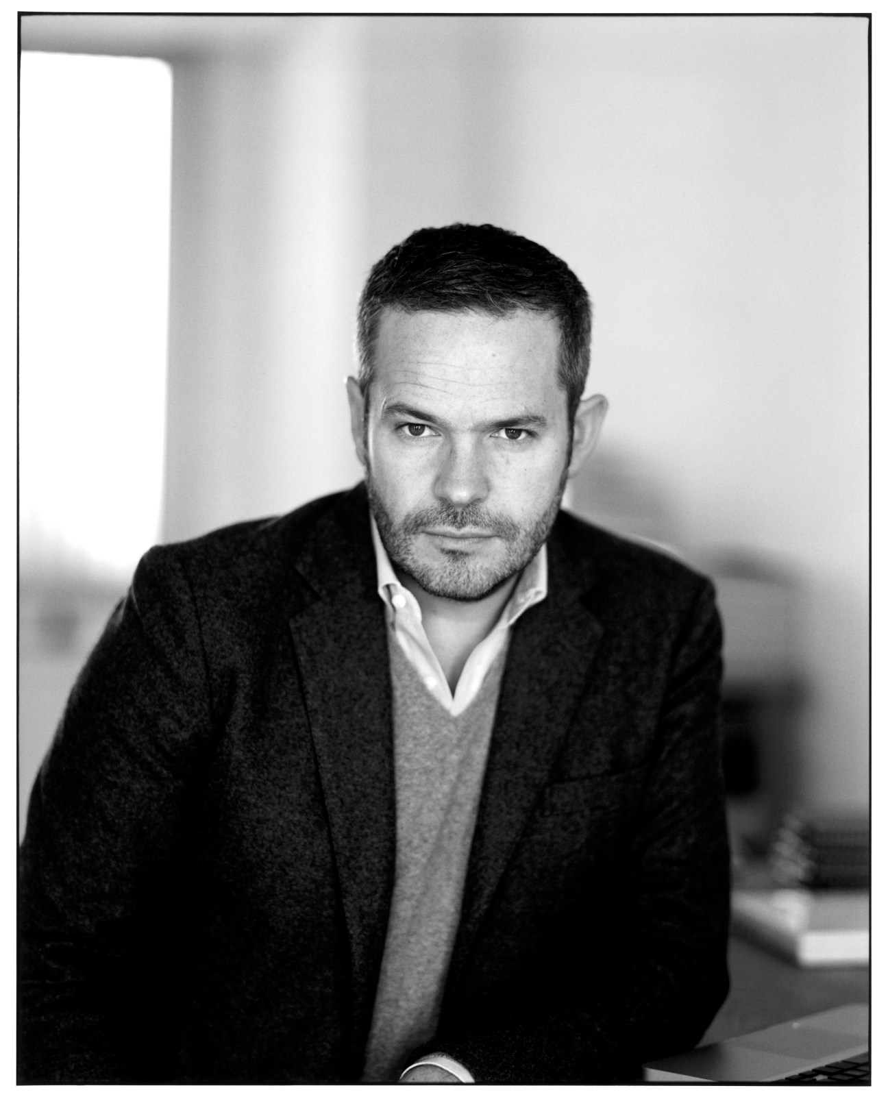 Black and white portrait of Tyler Brûlé, Monocle's editor in chief, wearing a dark blazer and gray sweater.