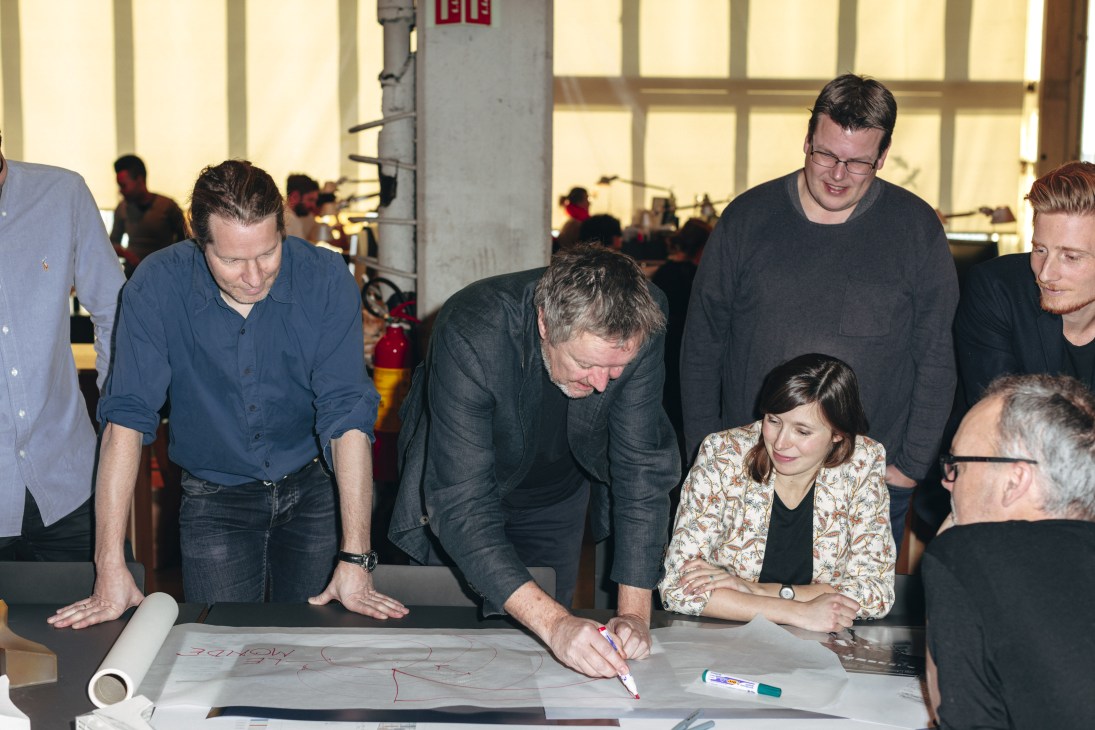 Architect Frank Denis Foray discusses Le Monde headquarters design with team members gathered around scaled architectural models.
