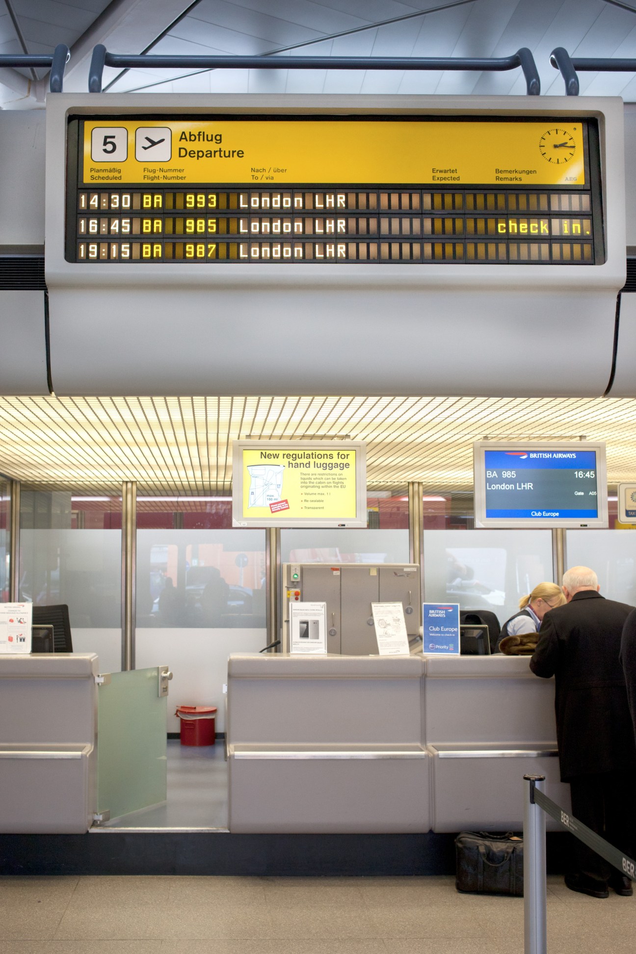 Tegel Airport departure board showing flights to London with check-in counters below.