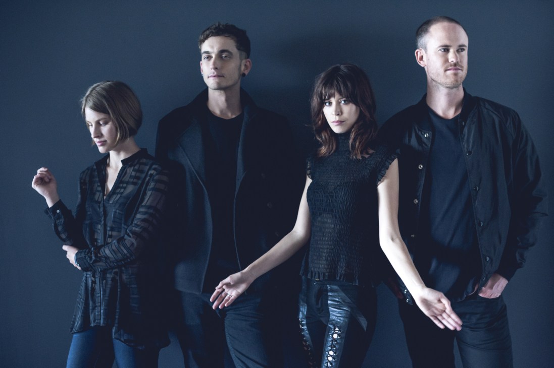 The Jezabels four-piece band posed against a blue background in dark clothing.