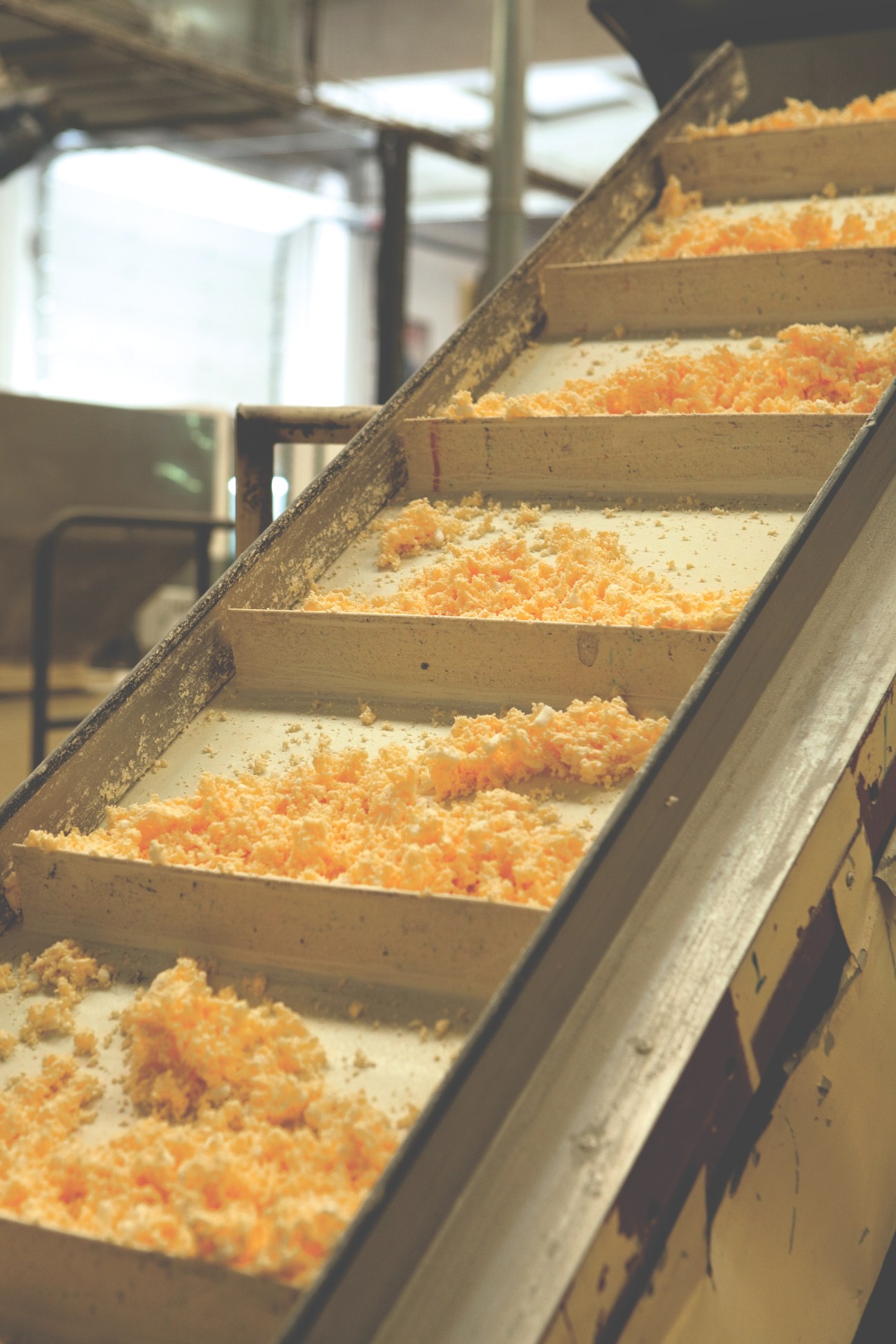 Soap paste in various stages of drying arranged in wooden trays on an assembly line.