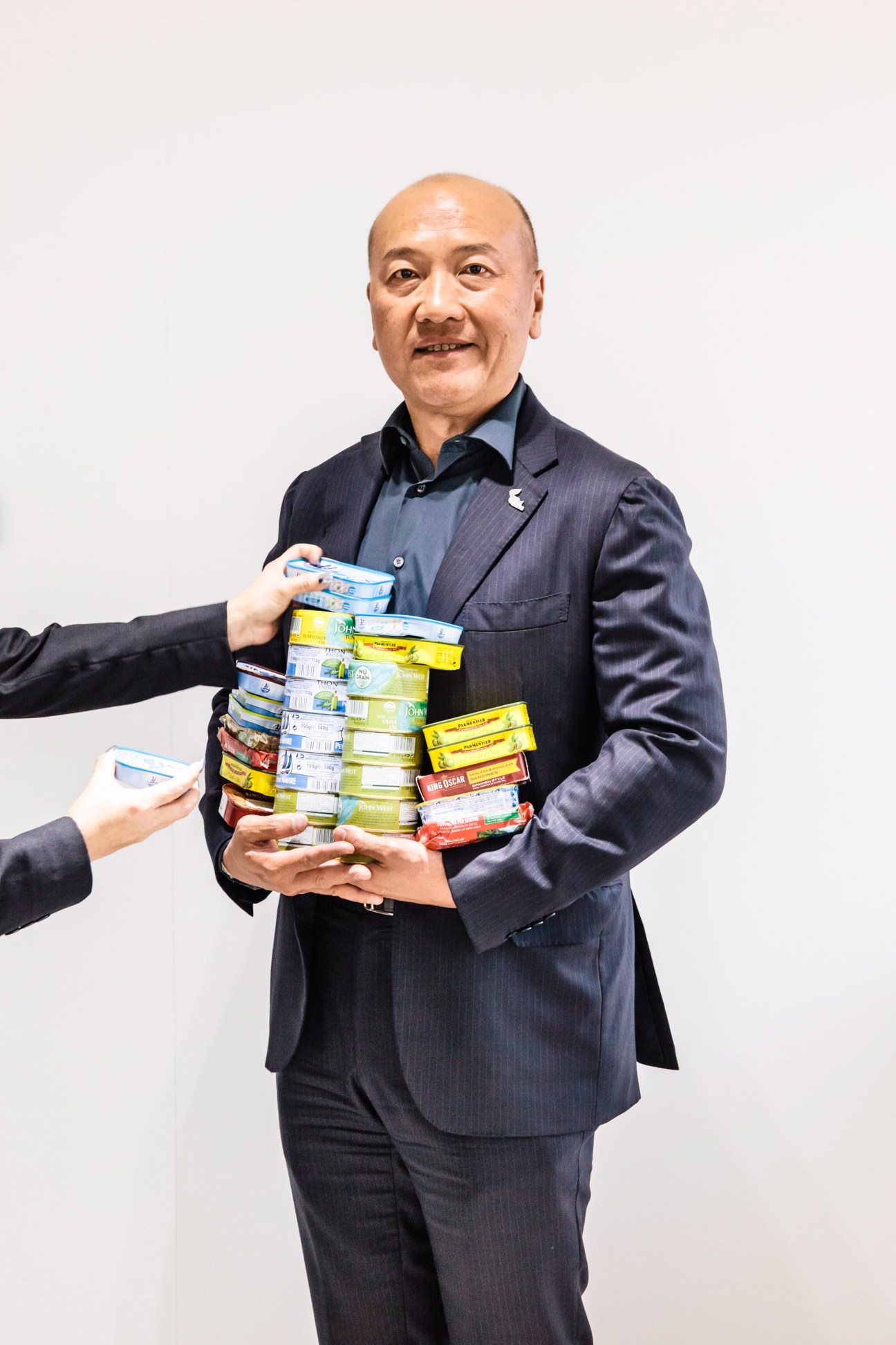 Thiraphong Chansiri holds a stack of canned seafood products including John West and other brands owned by Thai Union.