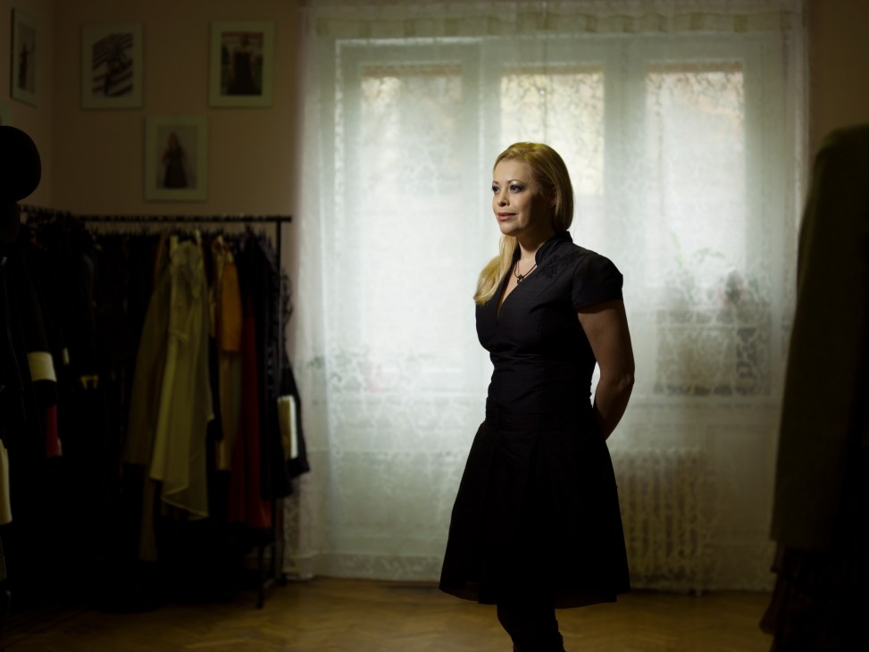 Fashion designer Tunde Hrivnak standing in her studio wearing a black wrap dress.