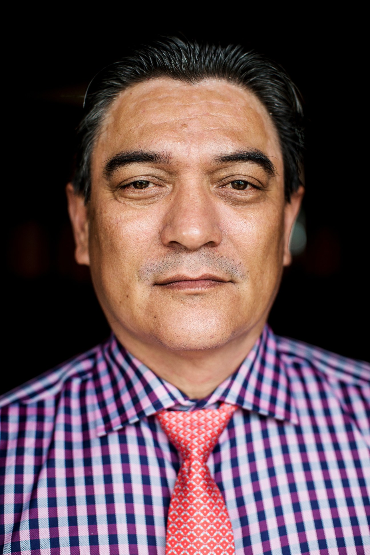 Portrait of Moana Carcasses Katokai Kalosil, Vanuatu's prime minister, wearing a checkered shirt and red tie.